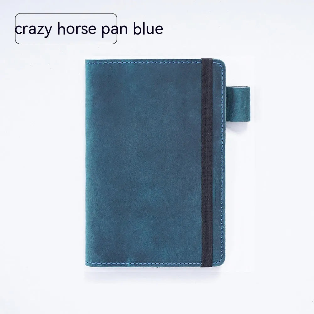 Handmade leather notebook in dark green, open on a desk showing wood-free paper pages.