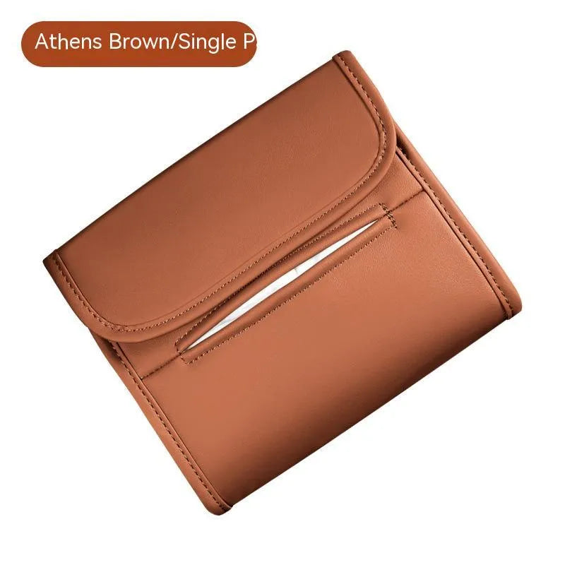 Brown leather car tissue box with elastic band hanging from a car sun visor