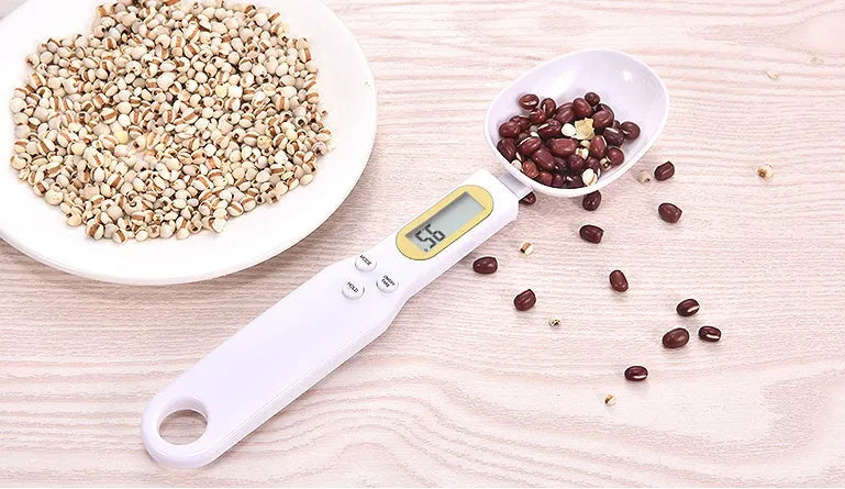 Black electronic measuring spoon scale showing digital display, placed on a kitchen counter.