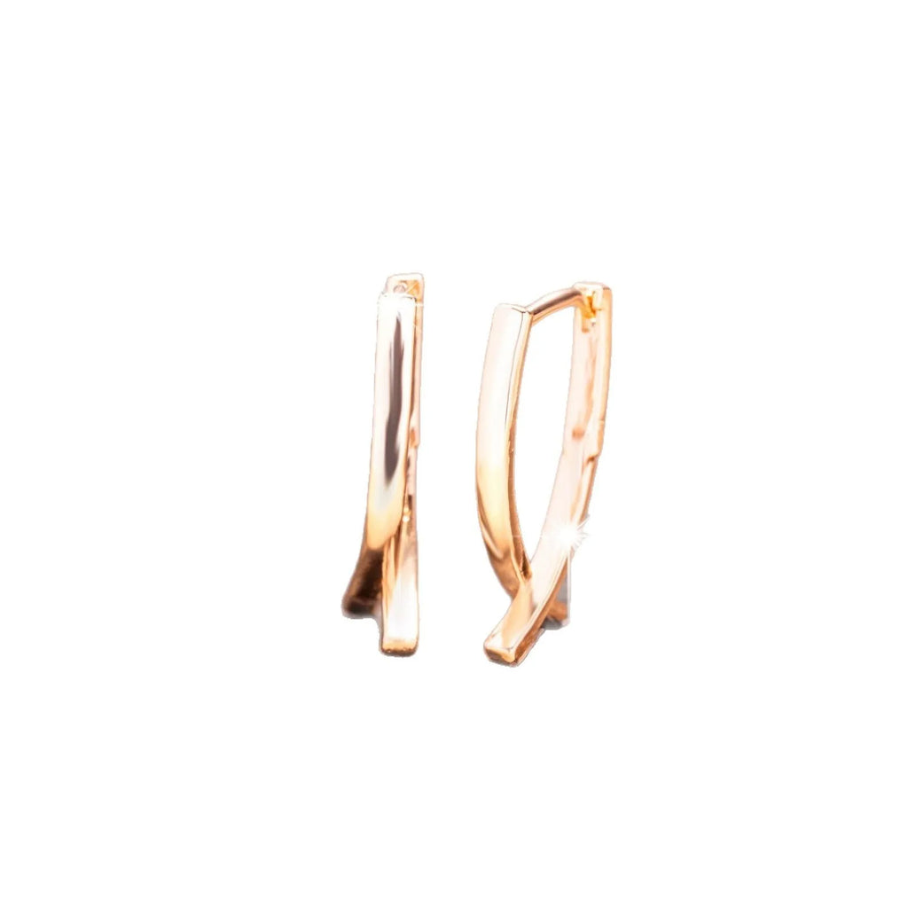 Rose gold coloured cross-shaped earrings on a plain background.