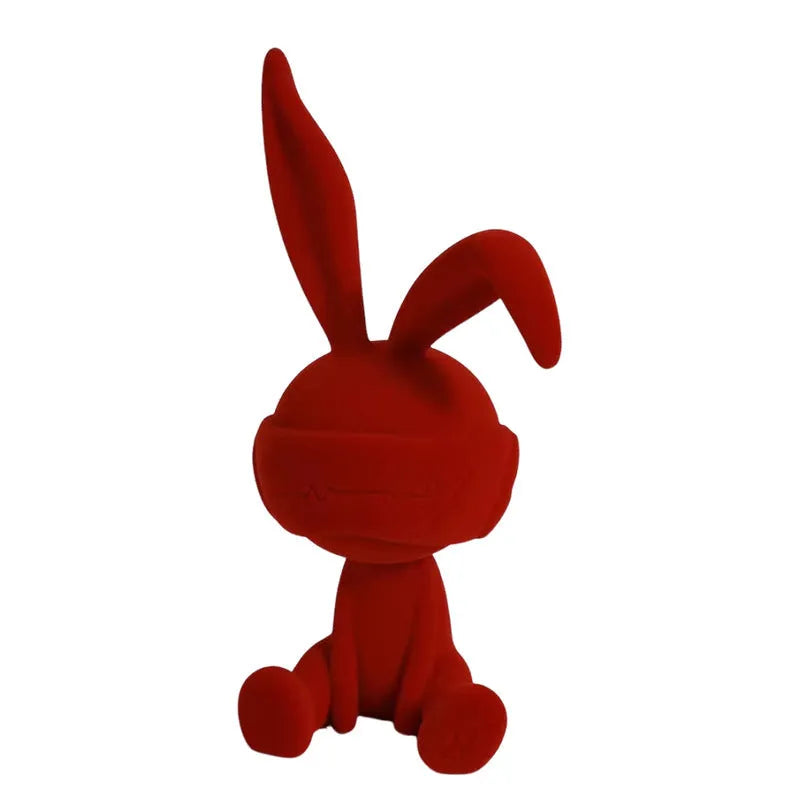 Suede blindfold rabbit resin ornament in green, blue, or red colours on a shelf.