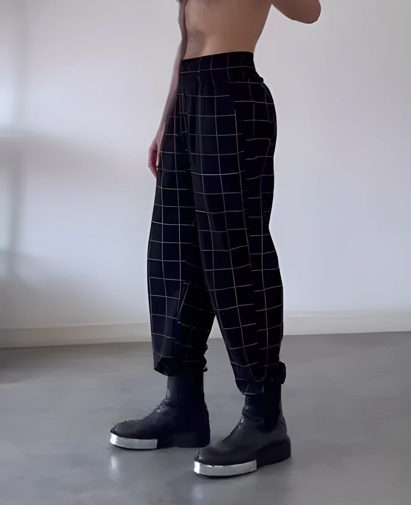 Man wearing grey plaid trousers with a contrasting darker apron panel across the front