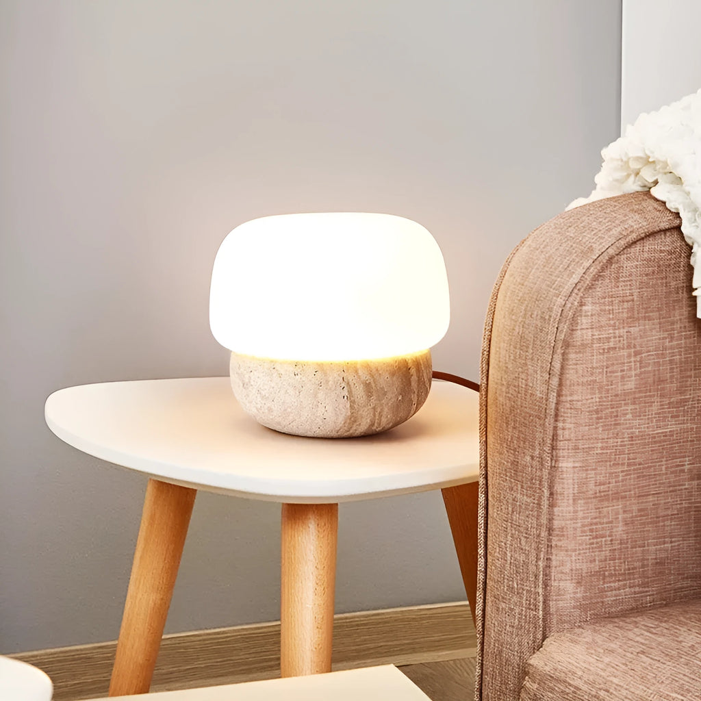 Cream-coloured retro style bedside lamp with a warm bulb on a table.
