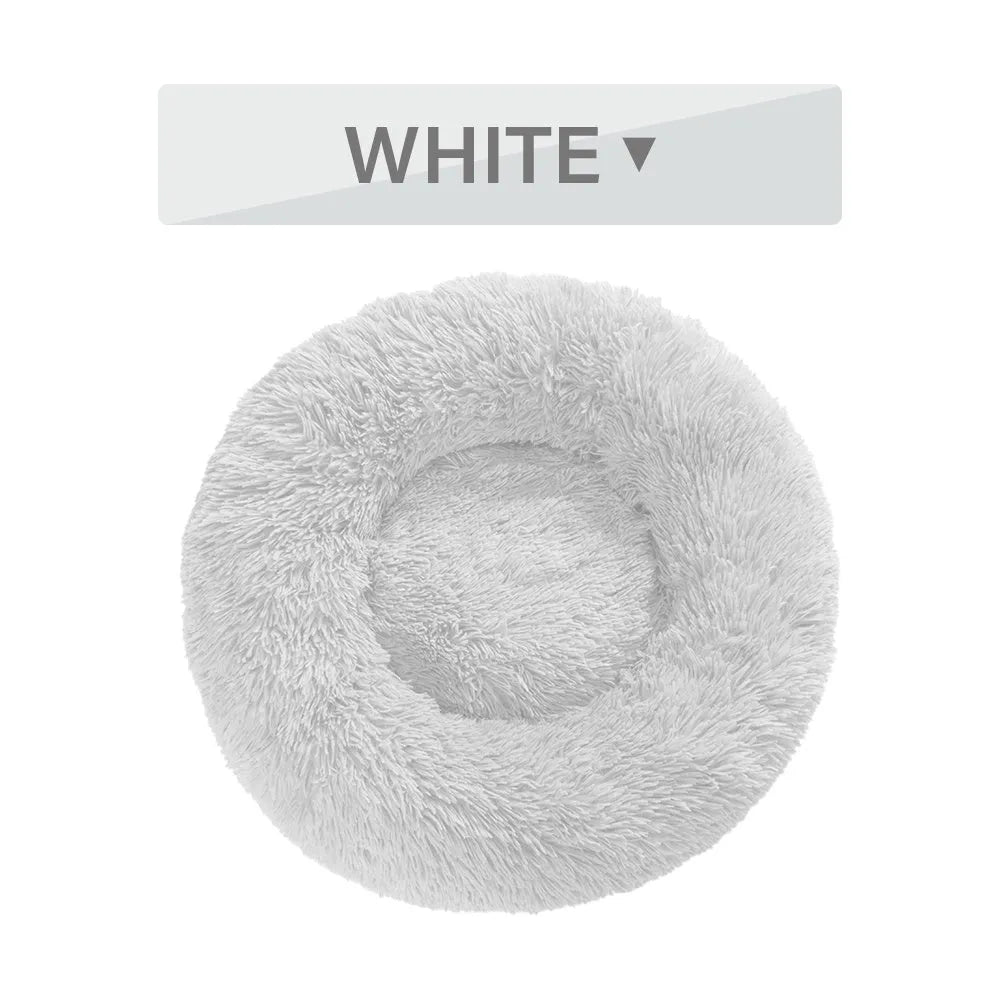 Fluffy donut-shaped dog bed in long plush material, shown in a grey colour, with a raised rim.
