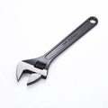 High carbon steel adjustable open-end spanner with black finish on a workbench.