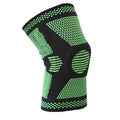 A green polyamide knee pad with a visible silicone spring and adjustable strap, laid flat.