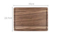 Solid black walnut wood cutting board with juice groove and side handle, shown in round and rectangular sizes.