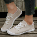 Creamy-white low-top fabric sneaker for women with a rubber sole on a neutral background