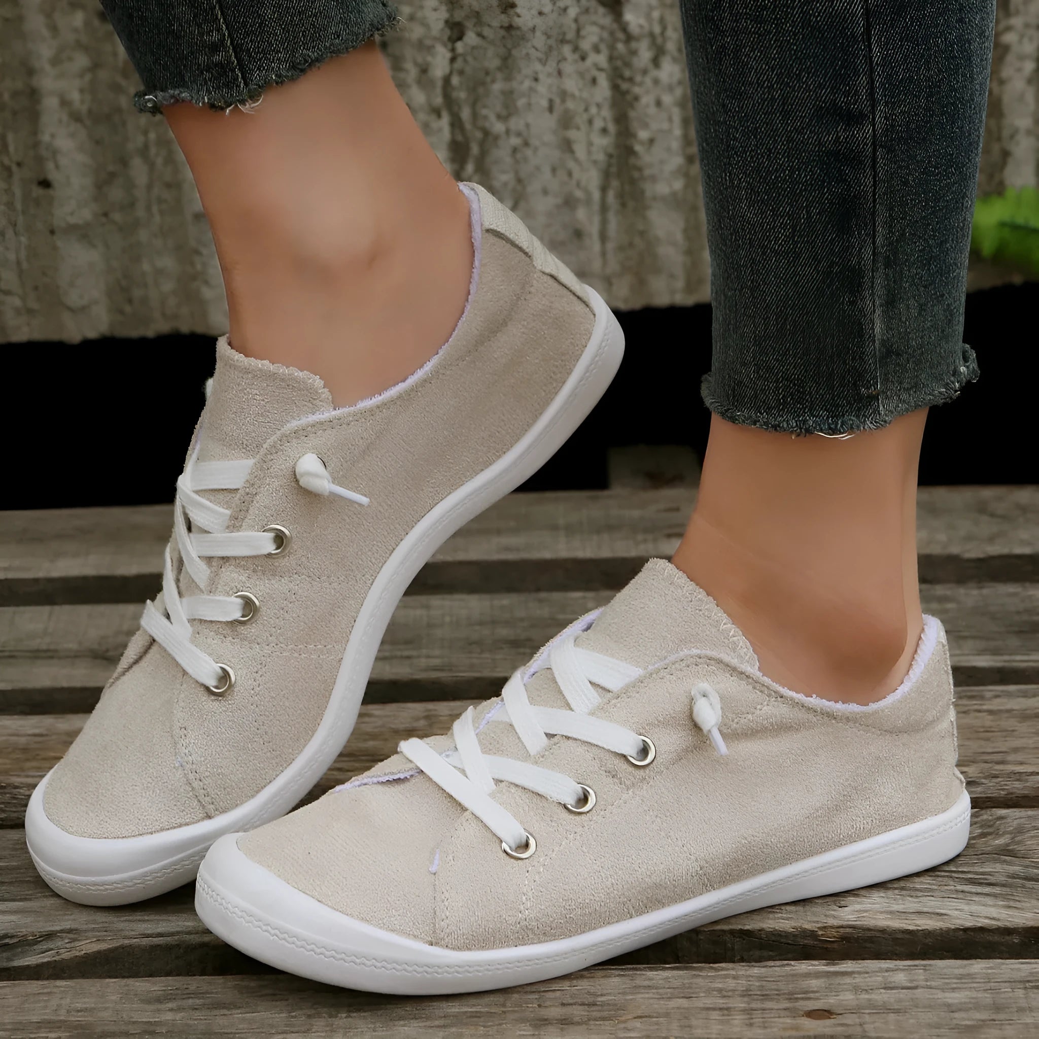 Creamy-white low-top fabric sneaker for women with a rubber sole on a neutral background