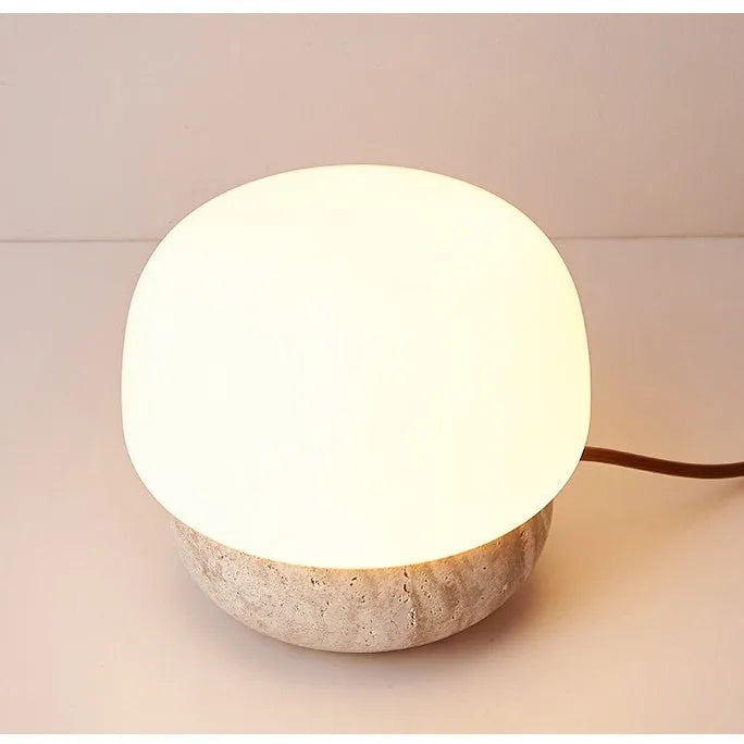 Cream-coloured retro style bedside lamp with a warm bulb on a table.