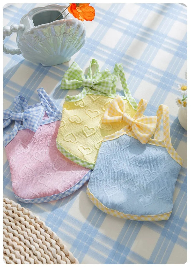 Small dog wearing blue elastic vest with heart texture and decorative bow