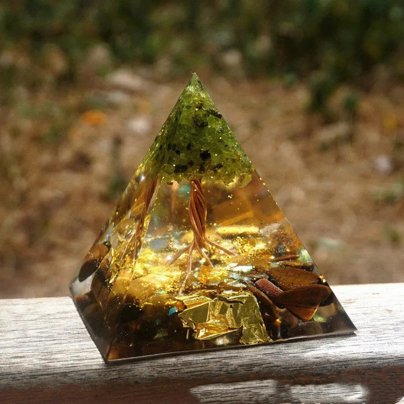 A 6cm high clear resin pyramid ornament filled with colourful crystal gravel on a wooden surface.