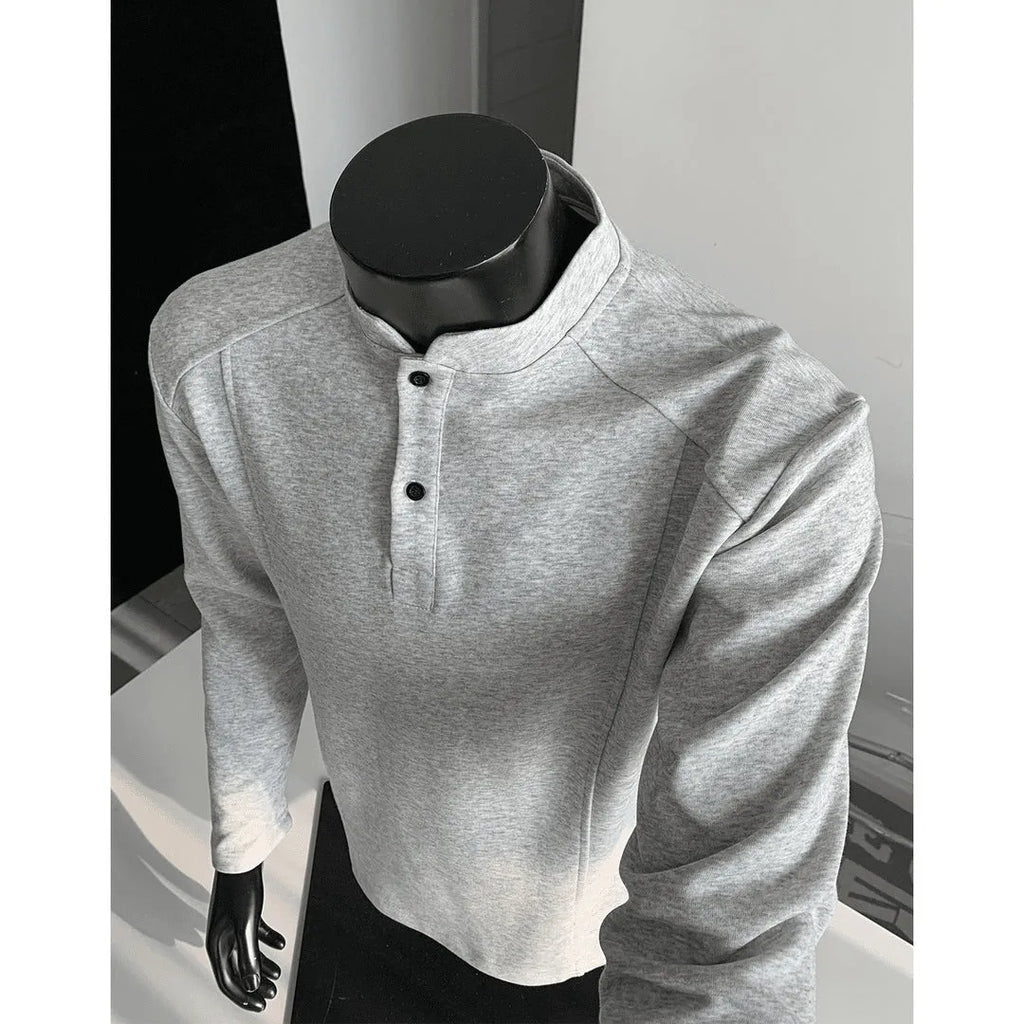 Man wearing a loose fit grey long sleeve sweater with an asymmetric design and a stand-up polo shirt collar.