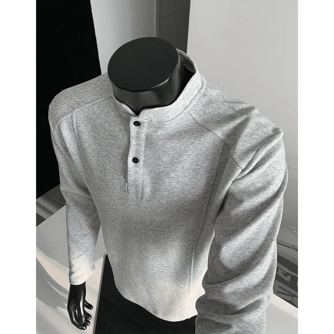 Man wearing a loose fit grey long sleeve sweater with an asymmetric design and a stand-up polo shirt collar.