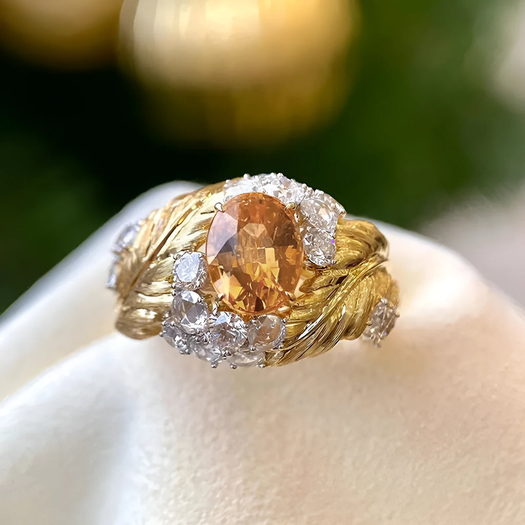 Gold-colour women's ring with a detailed embossed feather design and a central yellow zircon stone on a geometric copper band.