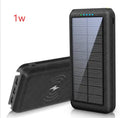 Black portable power bank with wireless charging surface and three USB ports for multiple device charging