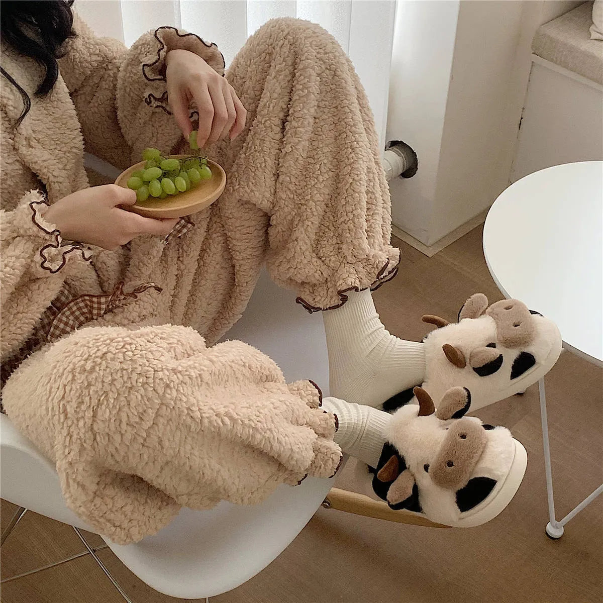 White cow print faux fur plush slippers for women with a non-slip textured sole.