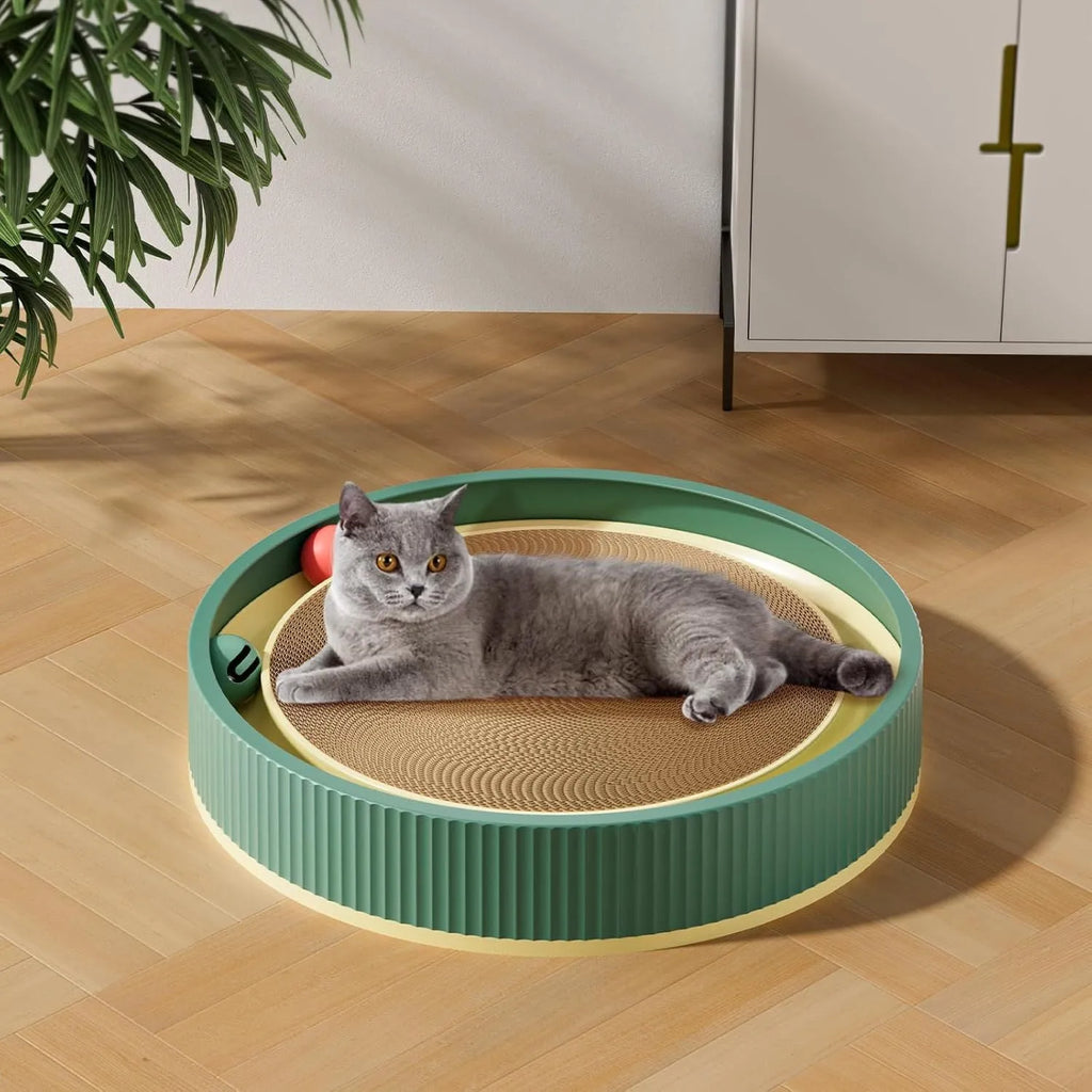 Large circular green cardboard cat scratching board with a central track containing two yellow balls and a spring-mounted plush ball.