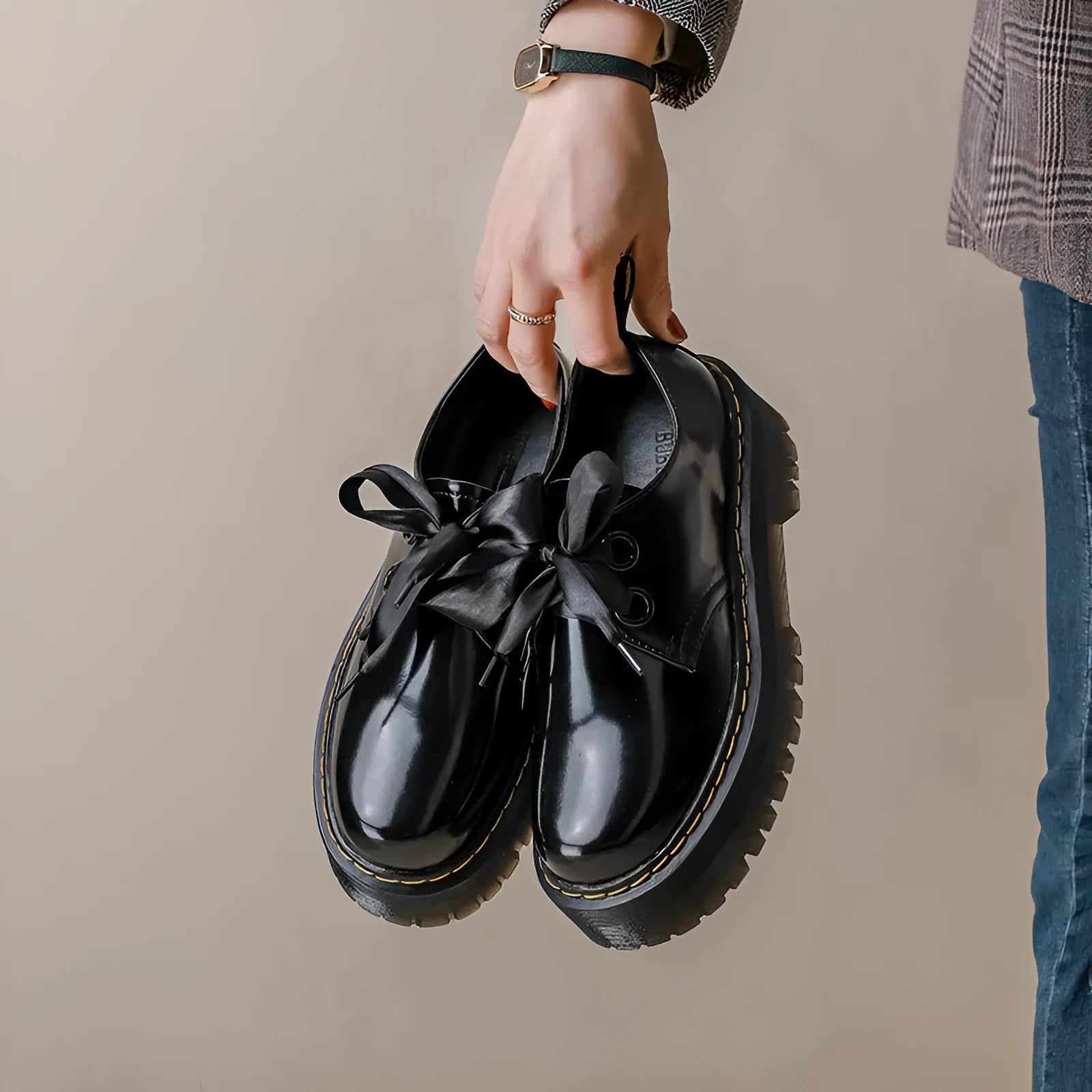 Women's black thick-soled leather-style lace-up shoes with ribbon and cross strap details on a white background.