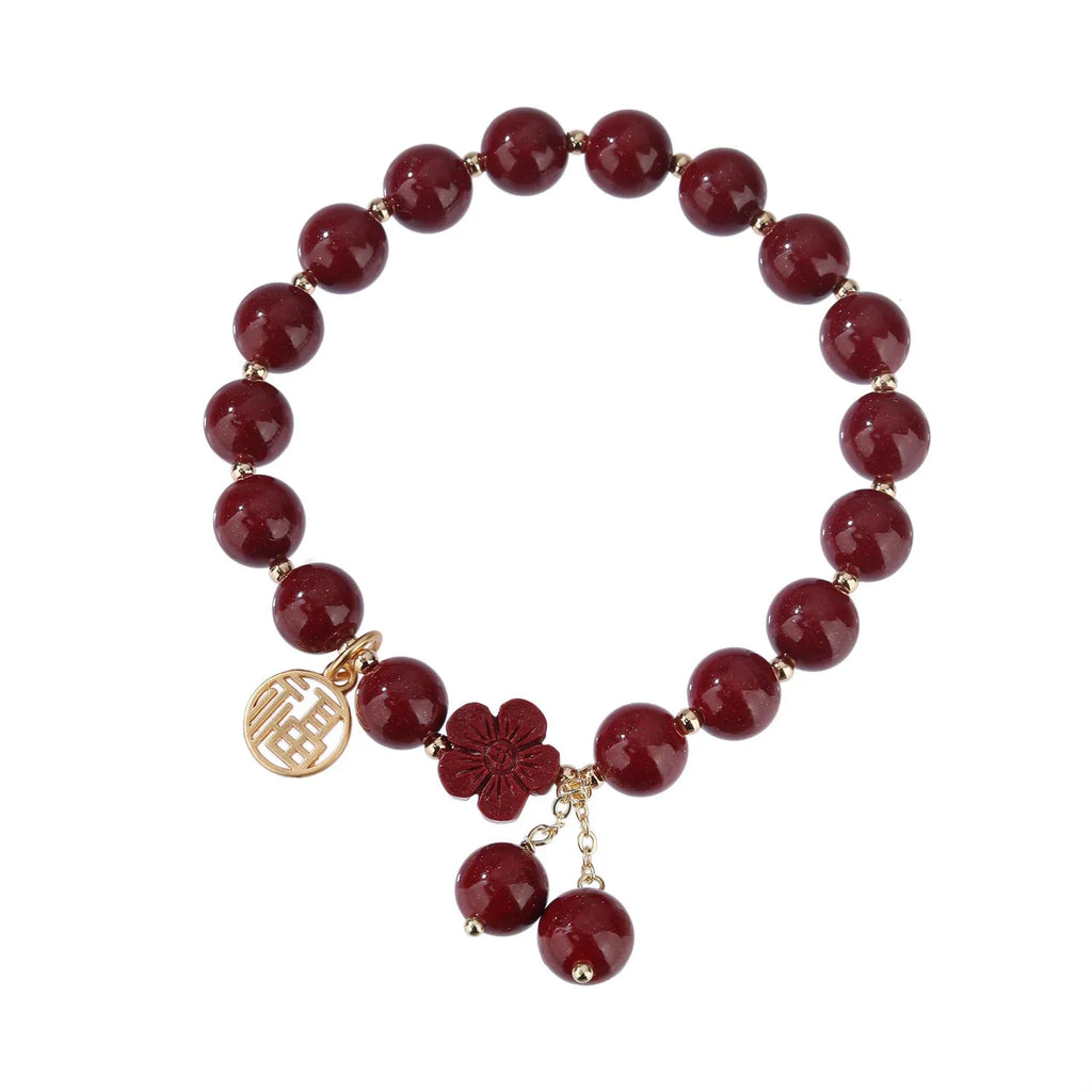 Close-up of a purple gold sand cinnabar bracelet with a fu character charm and adjustable tassel.