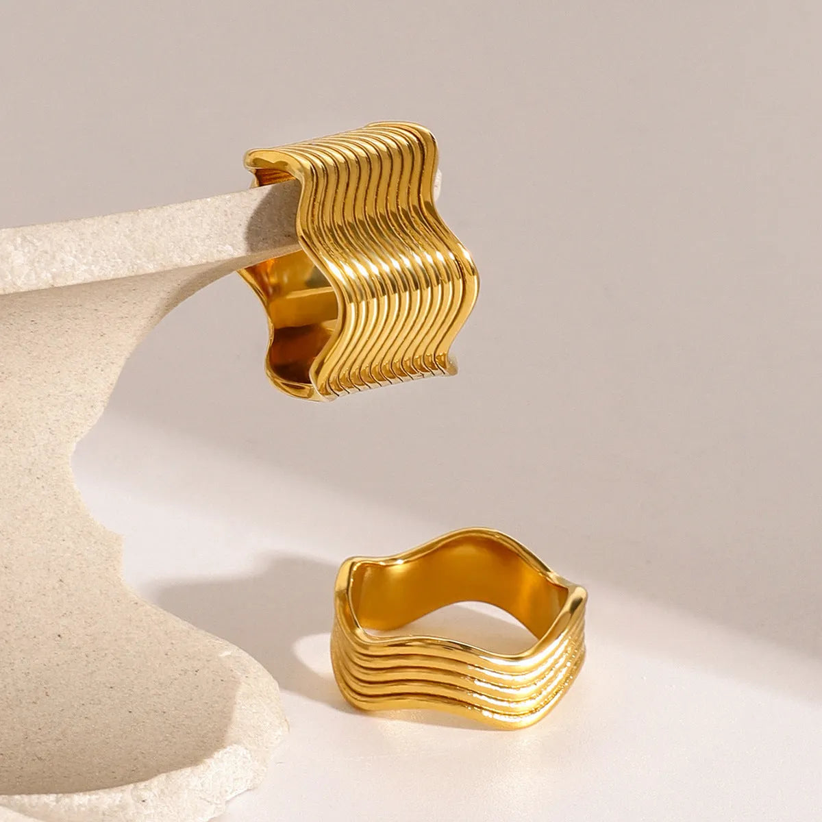 Stainless steel wide band ring with a geometric wave pattern in a metallic finish.