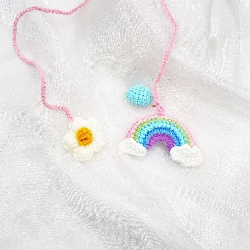 Handmade crocheted car pendant in avocado, pink rainbow, and red rainbow cartoon designs.