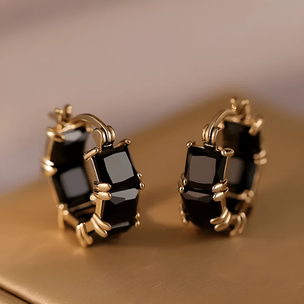 Geometric U-shaped gold tone earring with a round black zircon stone.