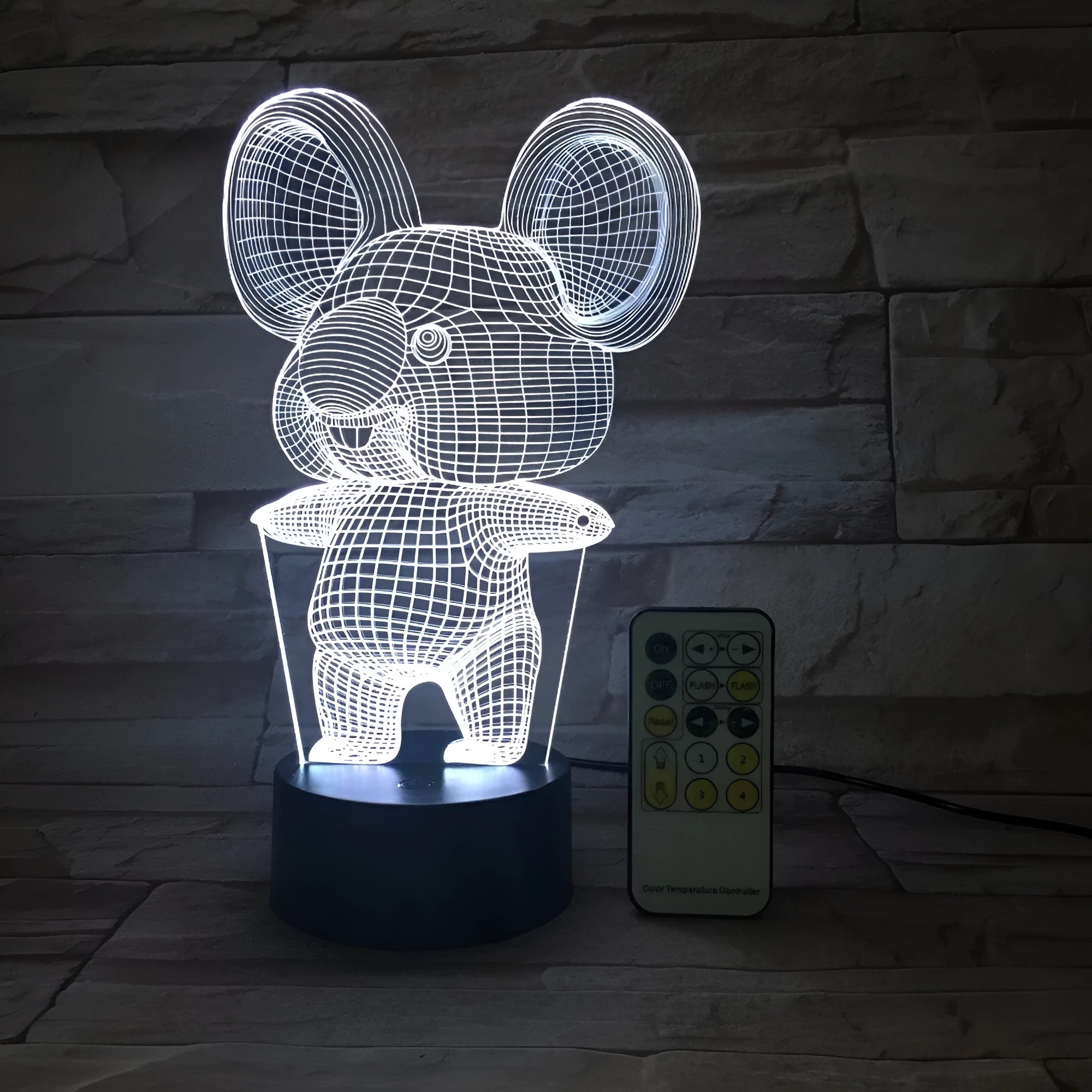 Black koala-shaped LED night light with remote control on a table, showing multi-colour illumination.
