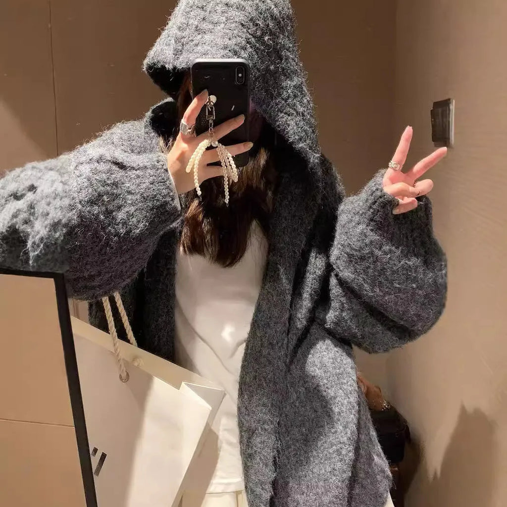 Woman wearing a dark gray retro-style hooded cardigan sweater with a loose fit.