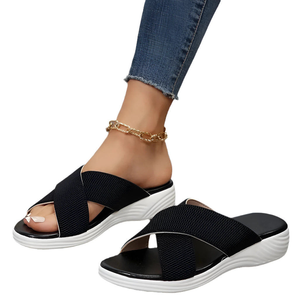 Women's black flat wedge slippers with peep toe and cross strap on a rubber sole.