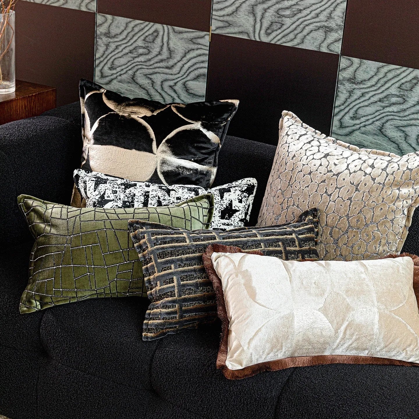 Black and gold abstract pattern flannel pillow cover on a grey sofa.