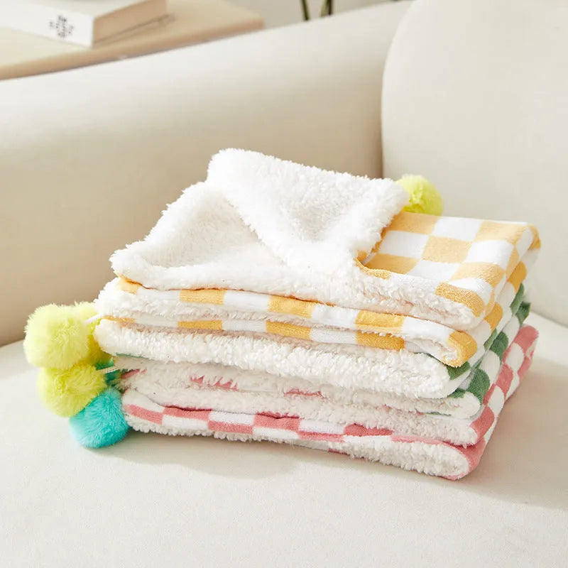 Green plush pet blanket with plaid pattern and fur balls as dog bed mat on sofa
