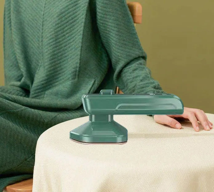 Dark green portable handheld hanging steam iron on a white background.