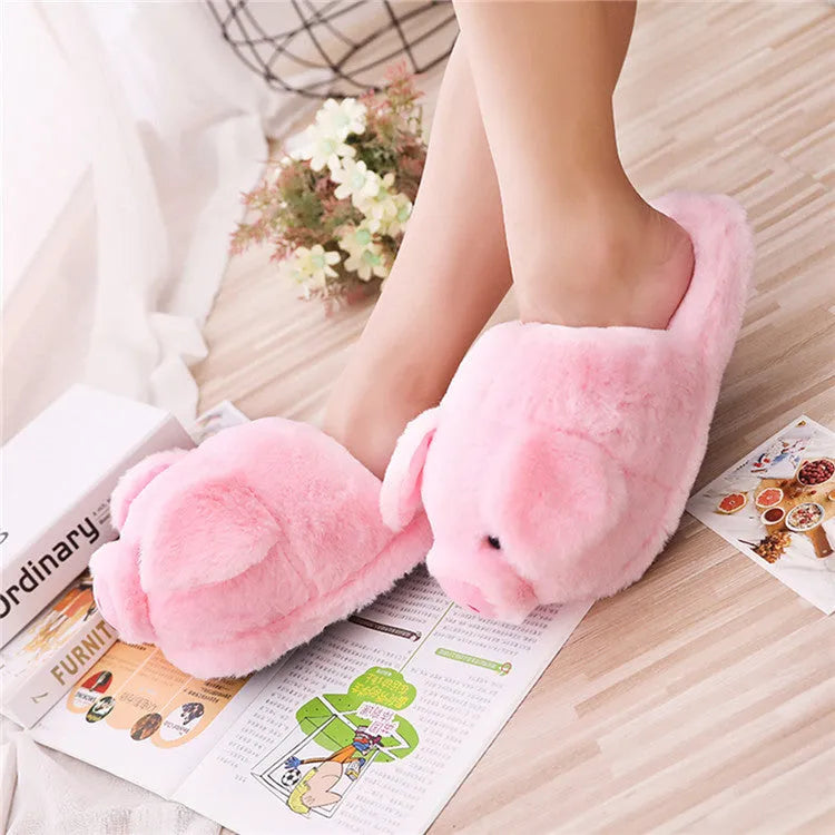Pink pig-shaped plush floor slippers for adults on a white background.