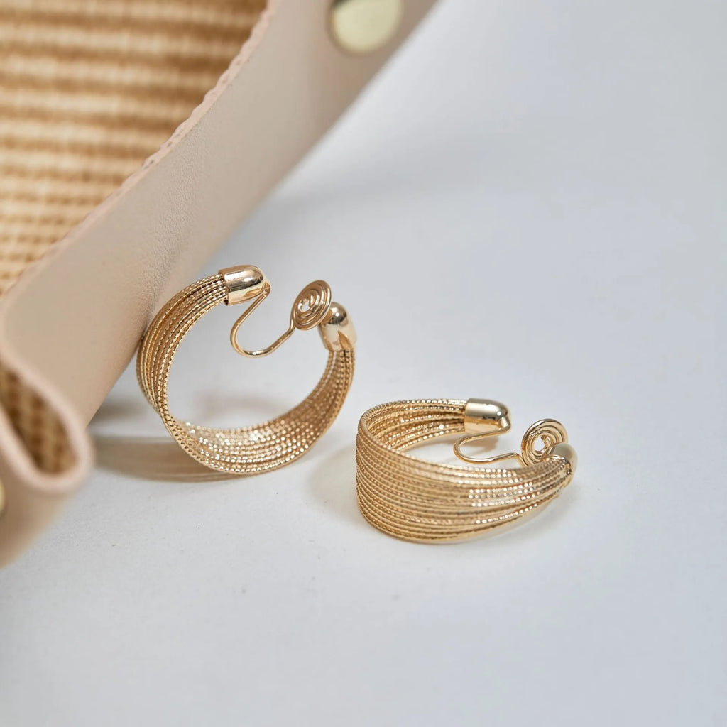 A pair of multi-layer geometric earrings in gold or silver electroplated finish, available as studs or clips.