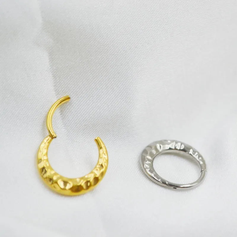 Close-up of a titanium alloy concave-convex nose ring in gold finish, showing detailed carving texture.