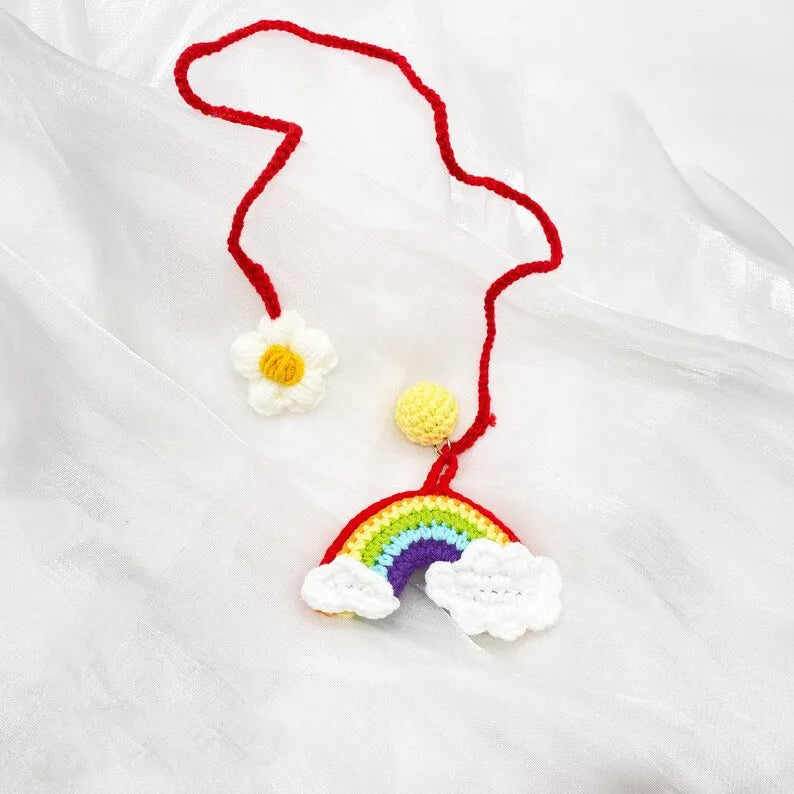 Handmade crocheted car pendant in avocado, pink rainbow, and red rainbow cartoon designs.