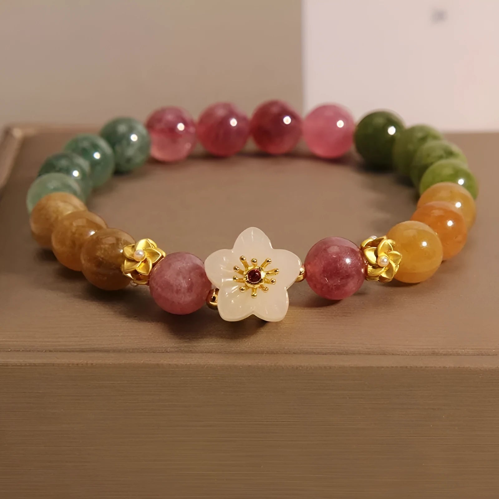 Tourmaline bracelet with floral or fu character design on a white background.