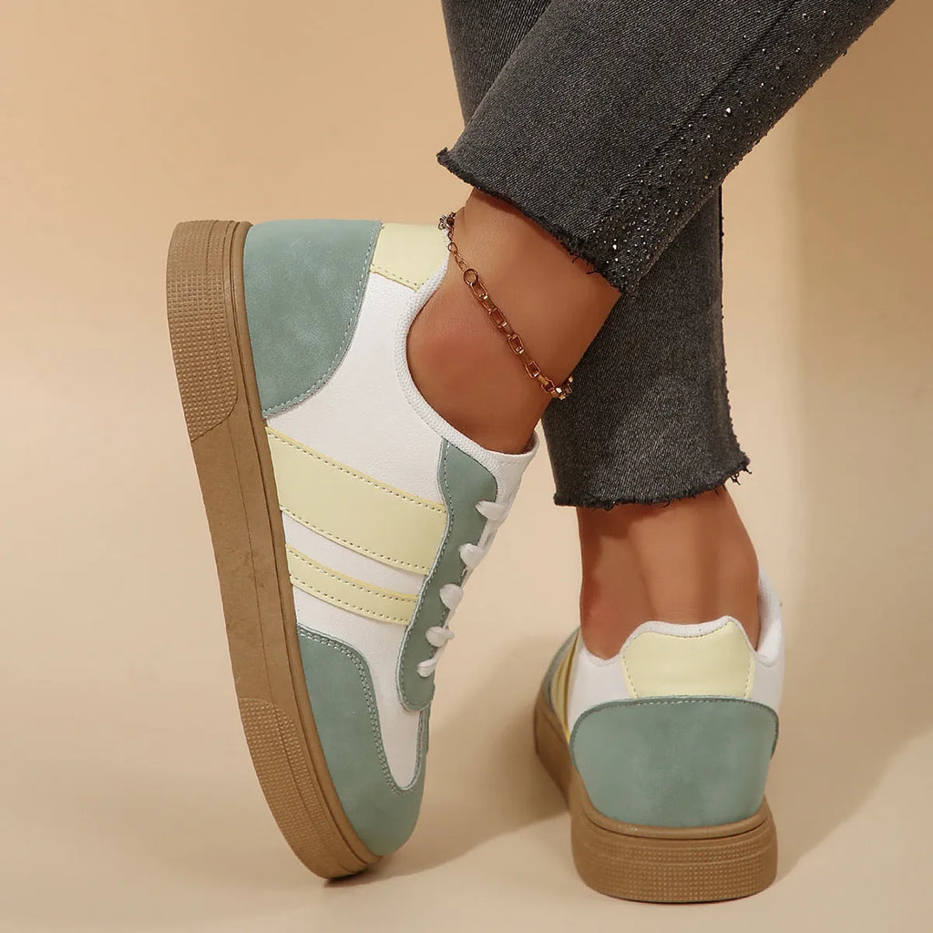 Green women's low-top retro sneakers with white cross straps and stitching on a PU upper.