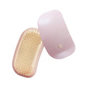 Light pink handheld electric pet massage brush with soft TPE teeth on a white background.