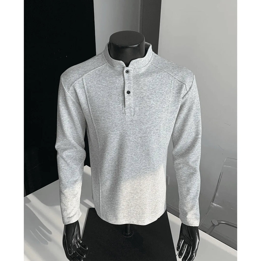 Man wearing a loose fit grey long sleeve sweater with an asymmetric design and a stand-up polo shirt collar.