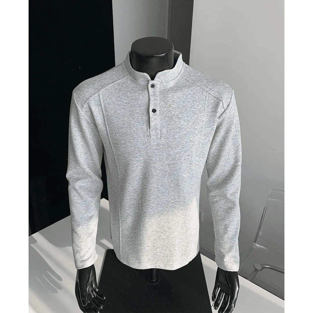Man wearing a loose fit grey long sleeve sweater with an asymmetric design and a stand-up polo shirt collar.