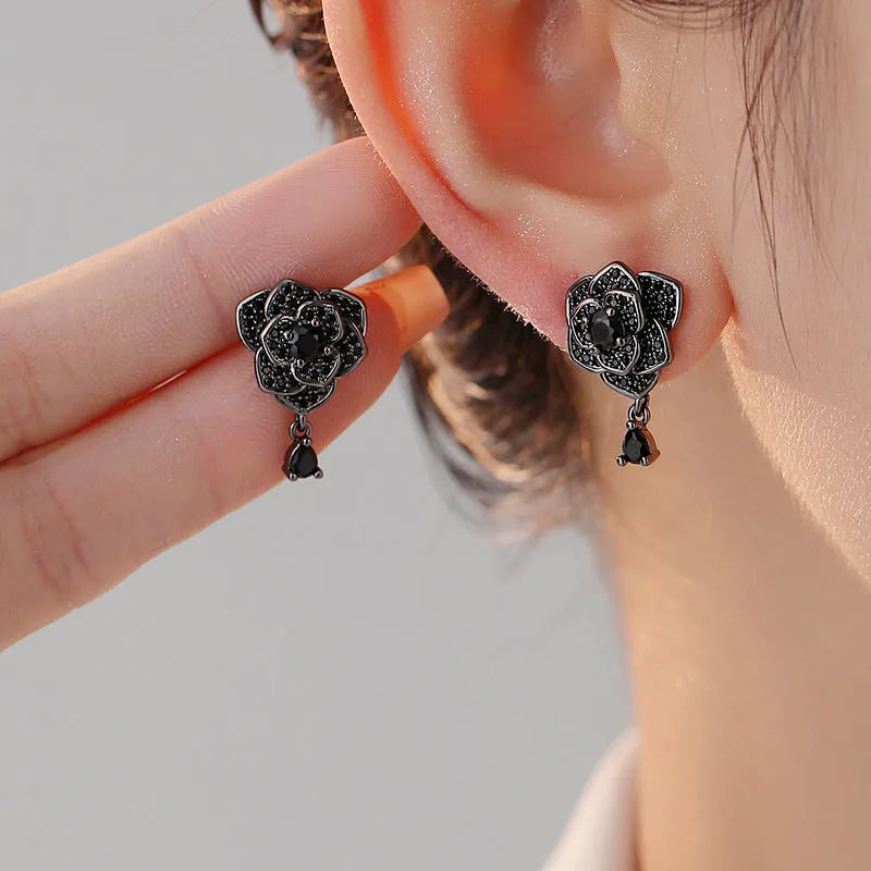 A pair of black rose zircon floral stud earrings with an 18K gold electroplated finish on copper.