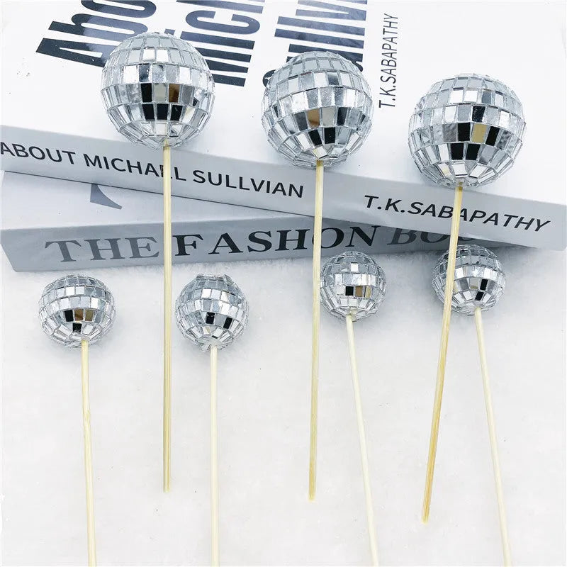 Glass disco ball cake decoration on a wooden stick, shown in different sizes.
