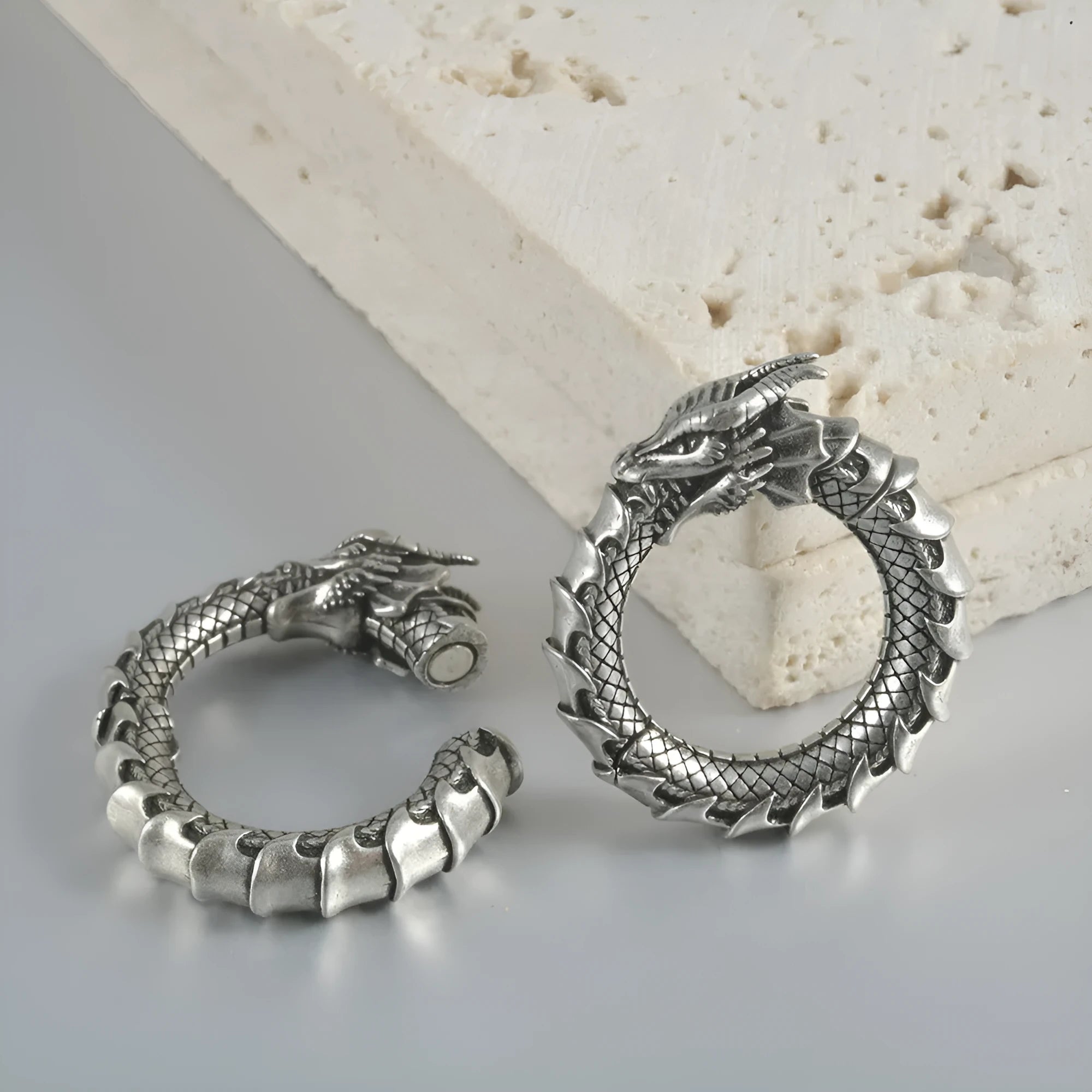 Large antique silver alloy earrings with a geometric hollow out dragon shape on a grey background.