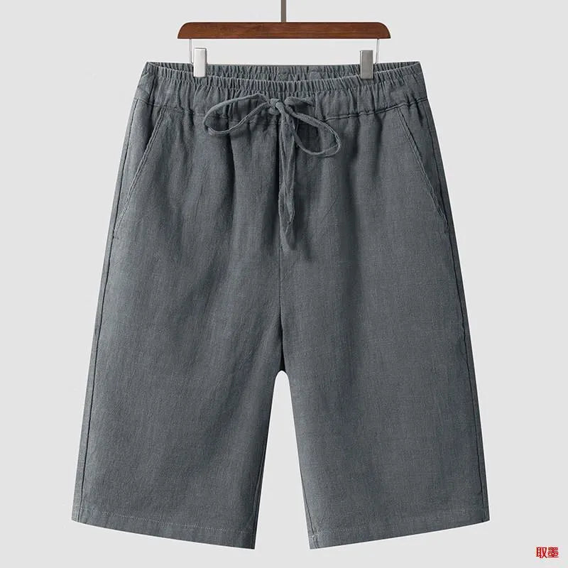 A pair of men's beige linen shorts with a loose, cropped cut and a mid-rise elasticated waistband.