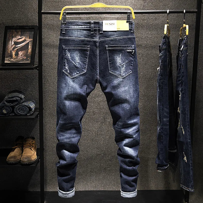 Men's slim-fit skinny jeans in dark blue denim laid flat, showing front design and button fly.