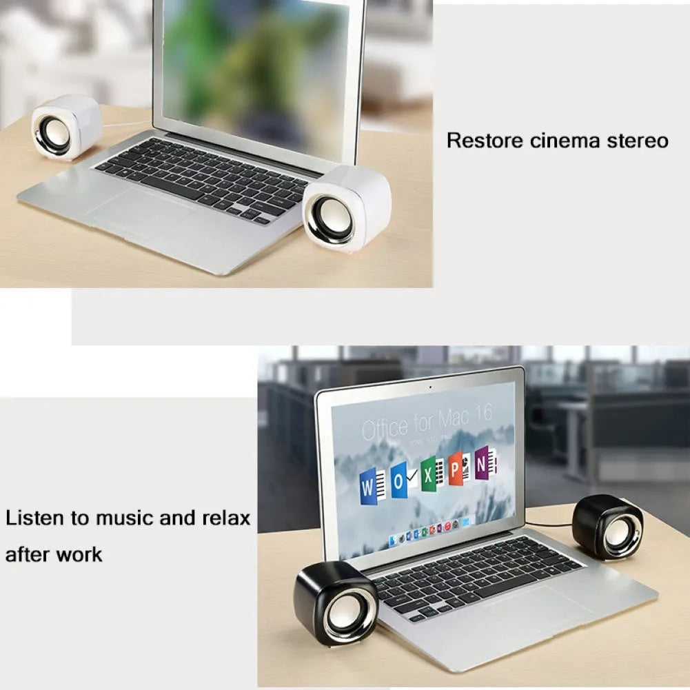 Pair of small black cube-shaped wired computer speakers with a 3.5mm plug on a desk