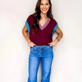 Burgundy loose V-neck sweater with short cuffed sleeves and contrast trim detail.