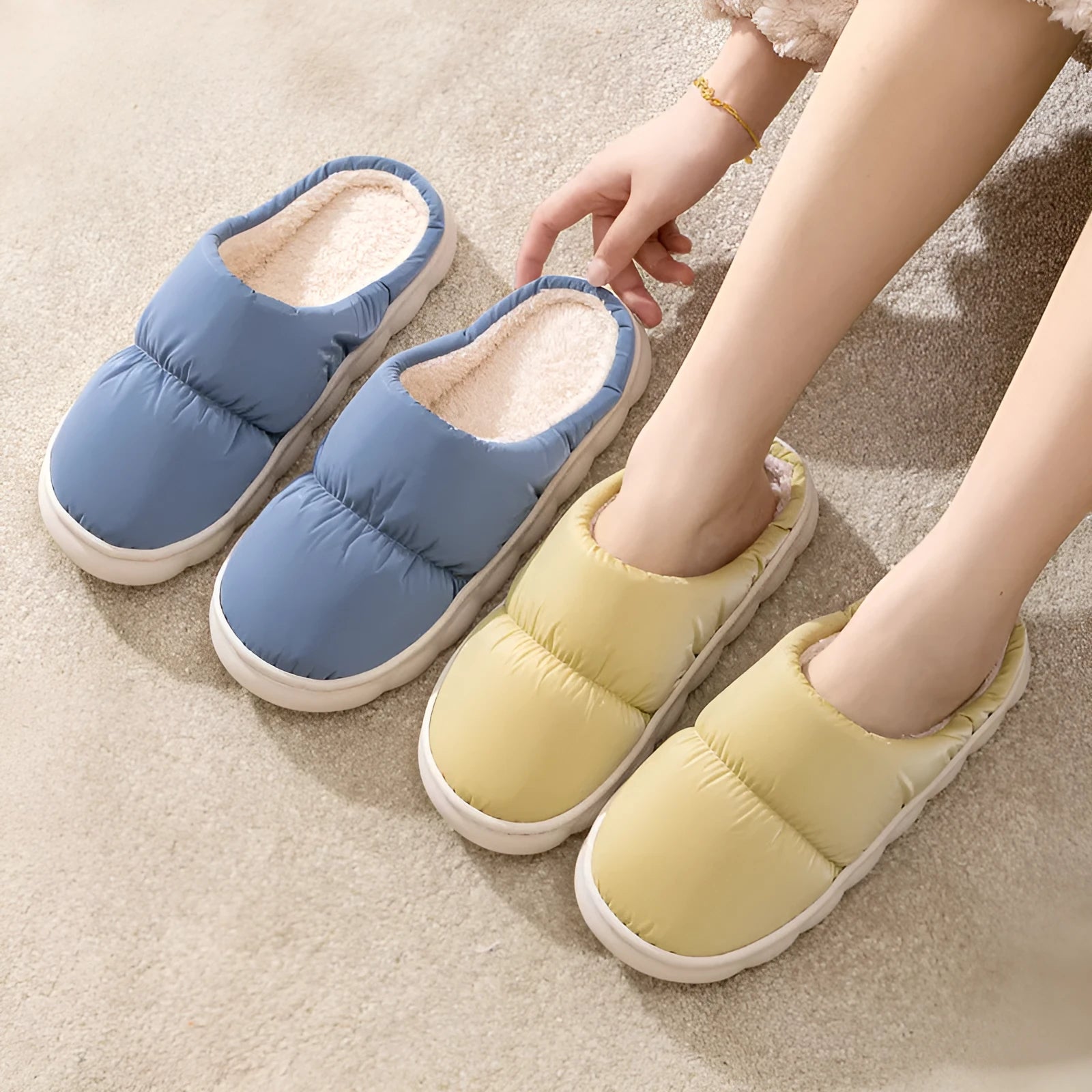 A pair of blue down cotton slippers with a thick rubber sole and artificial leather upper on a wooden floor.